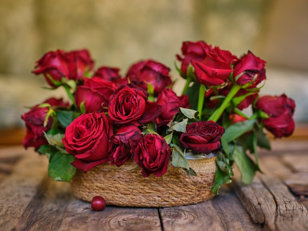 a basket filled with red roses on top of a wooden table