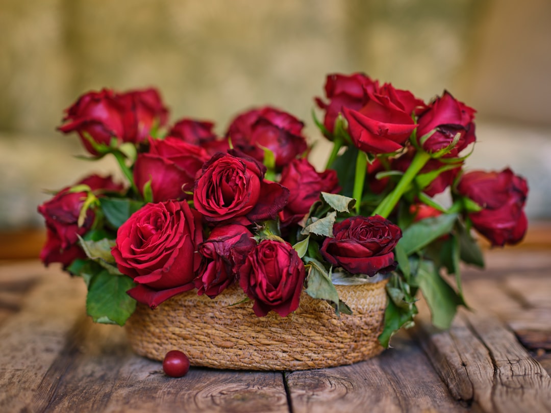 a basket filled with red roses on top of a wooden table